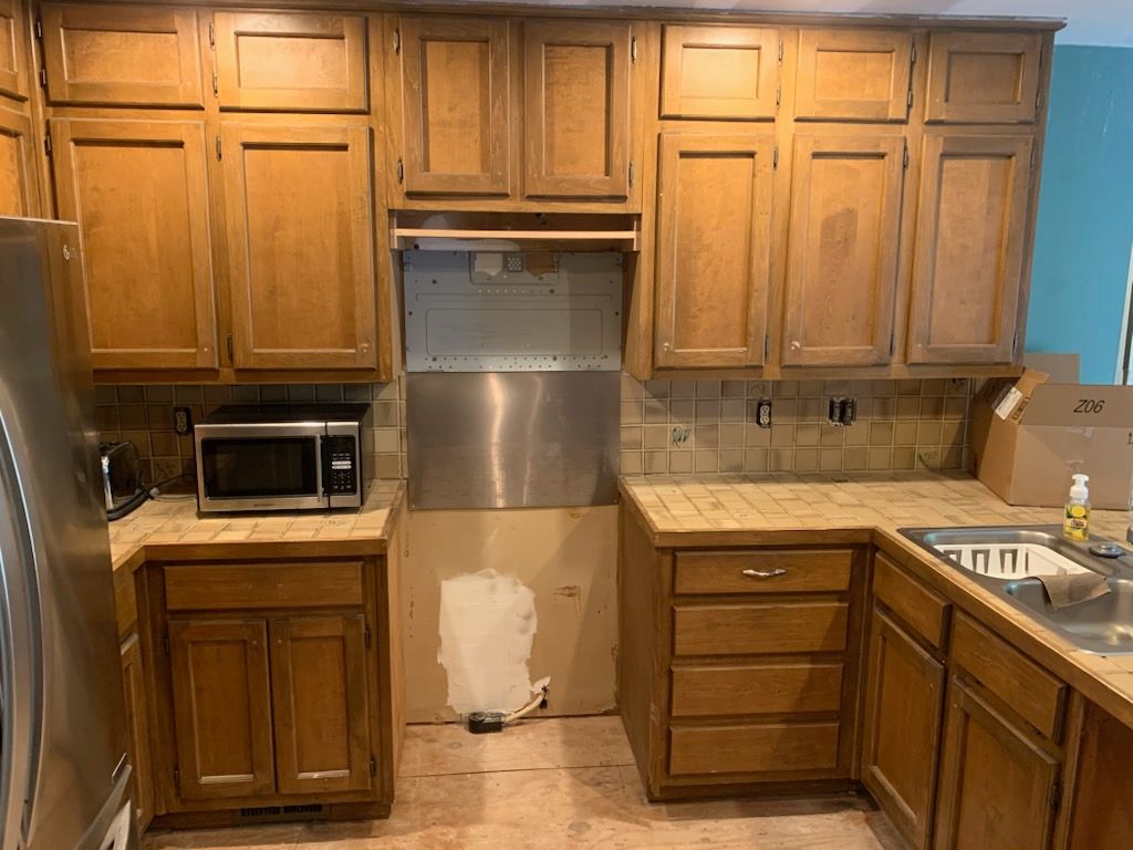 Spacious bathroom with wood cabinets, a soaking tub, large mirror, and polished hardwood floors.