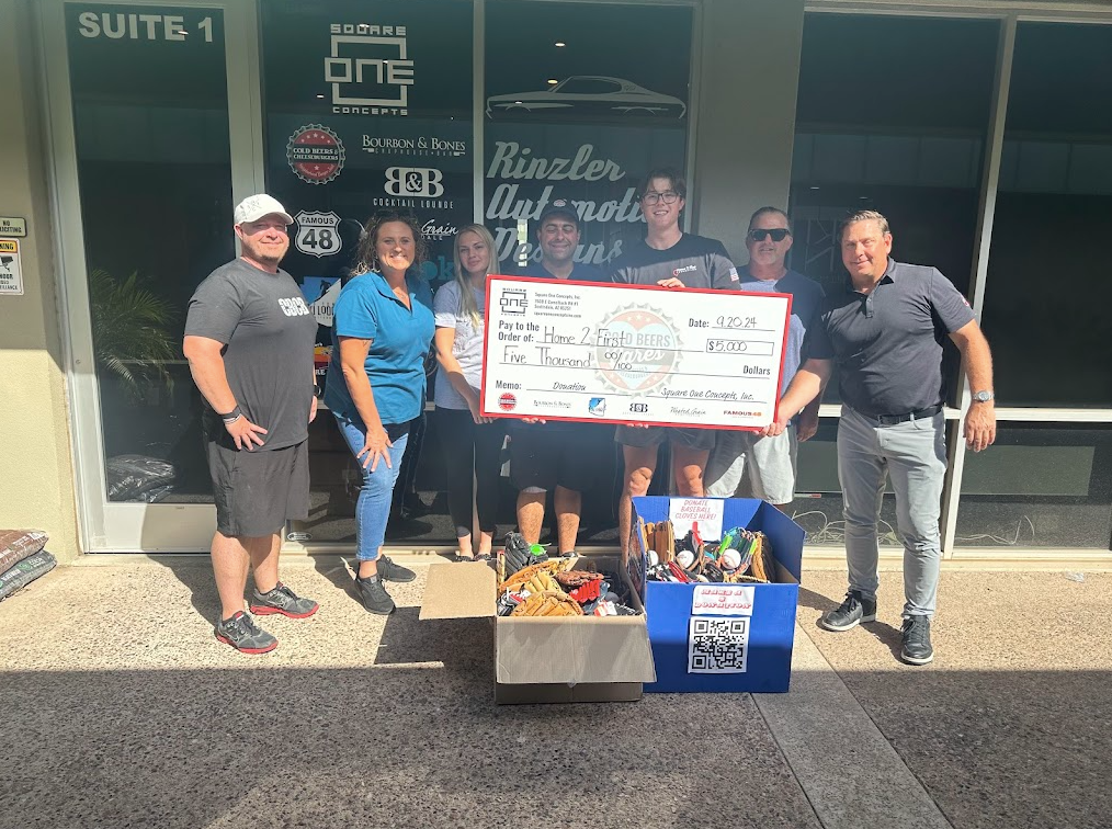 A group of people standing in front of a building holding a large check.