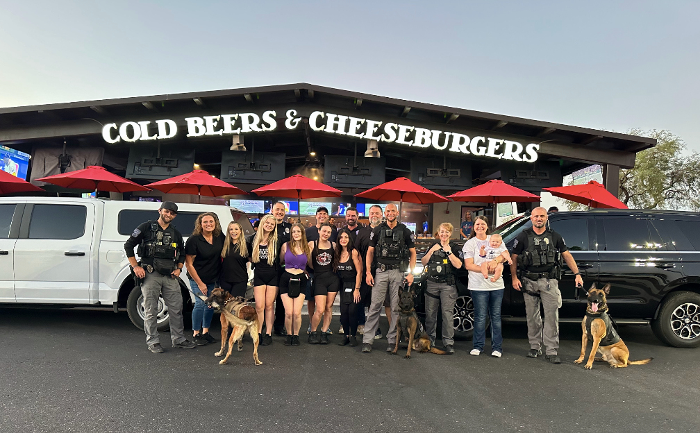 A group of people standing in front of a building that says cold beers and cheeseburgers.