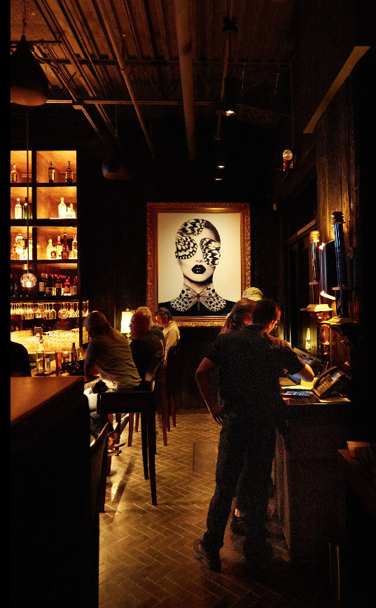 A group of people in a dark room with a painting on the wall