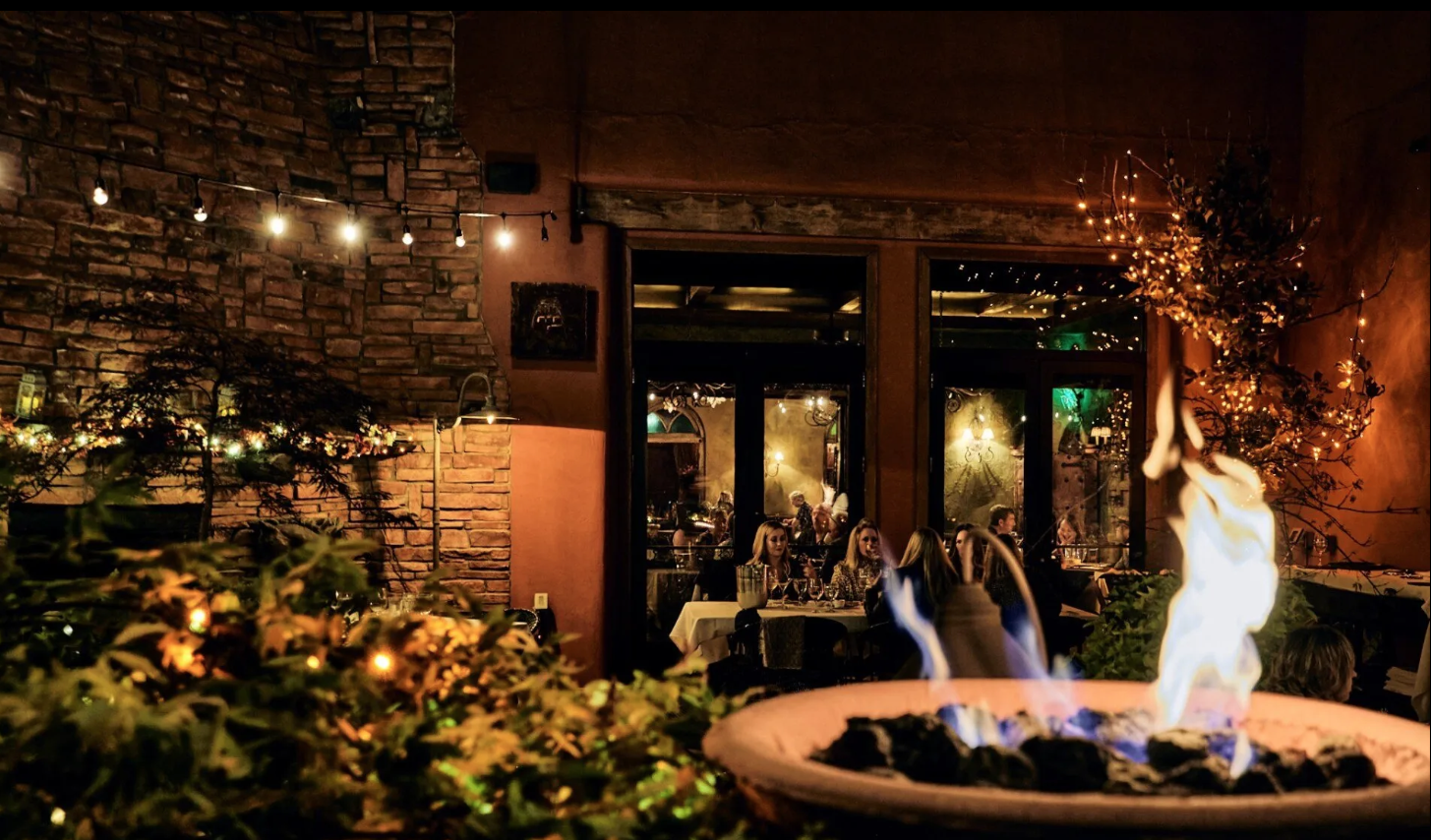 A fire pit is lit up in front of a restaurant at night.