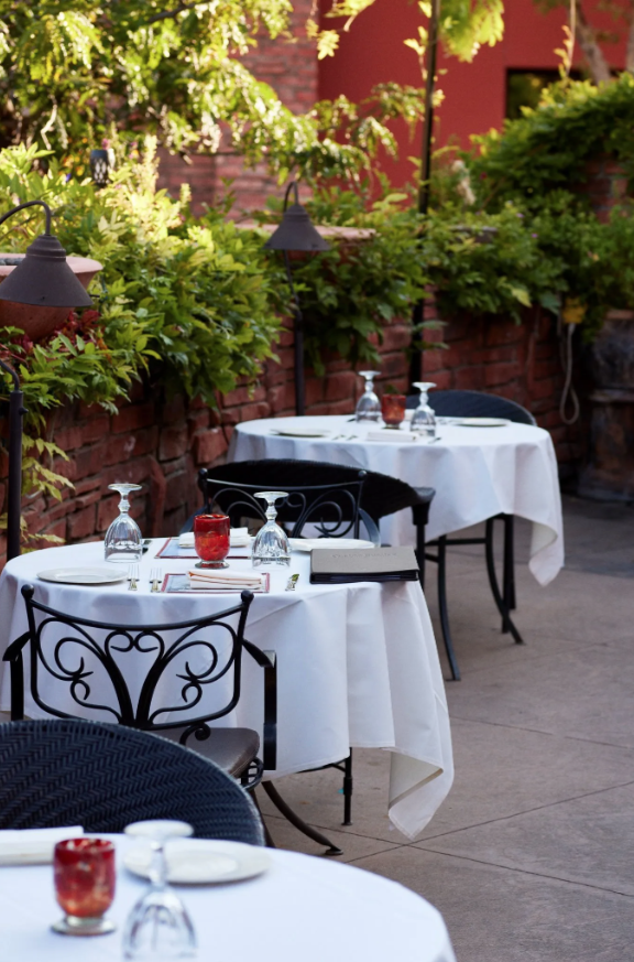 A restaurant patio with tables and chairs set for dinner