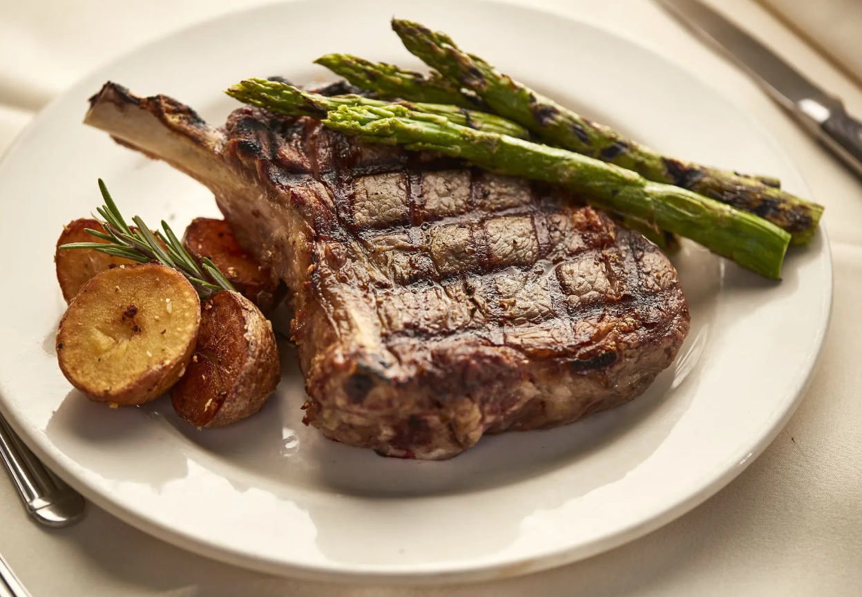 A white plate topped with a steak asparagus and potatoes