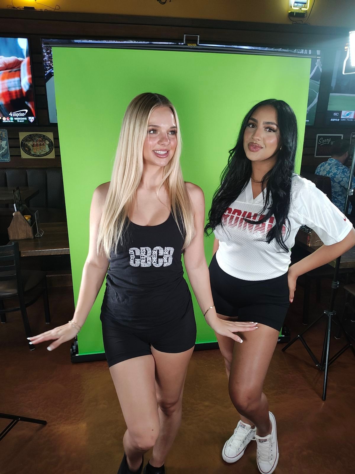 Two women are standing next to each other in front of a green screen.