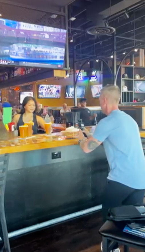 A man is sitting at a bar talking to a woman.