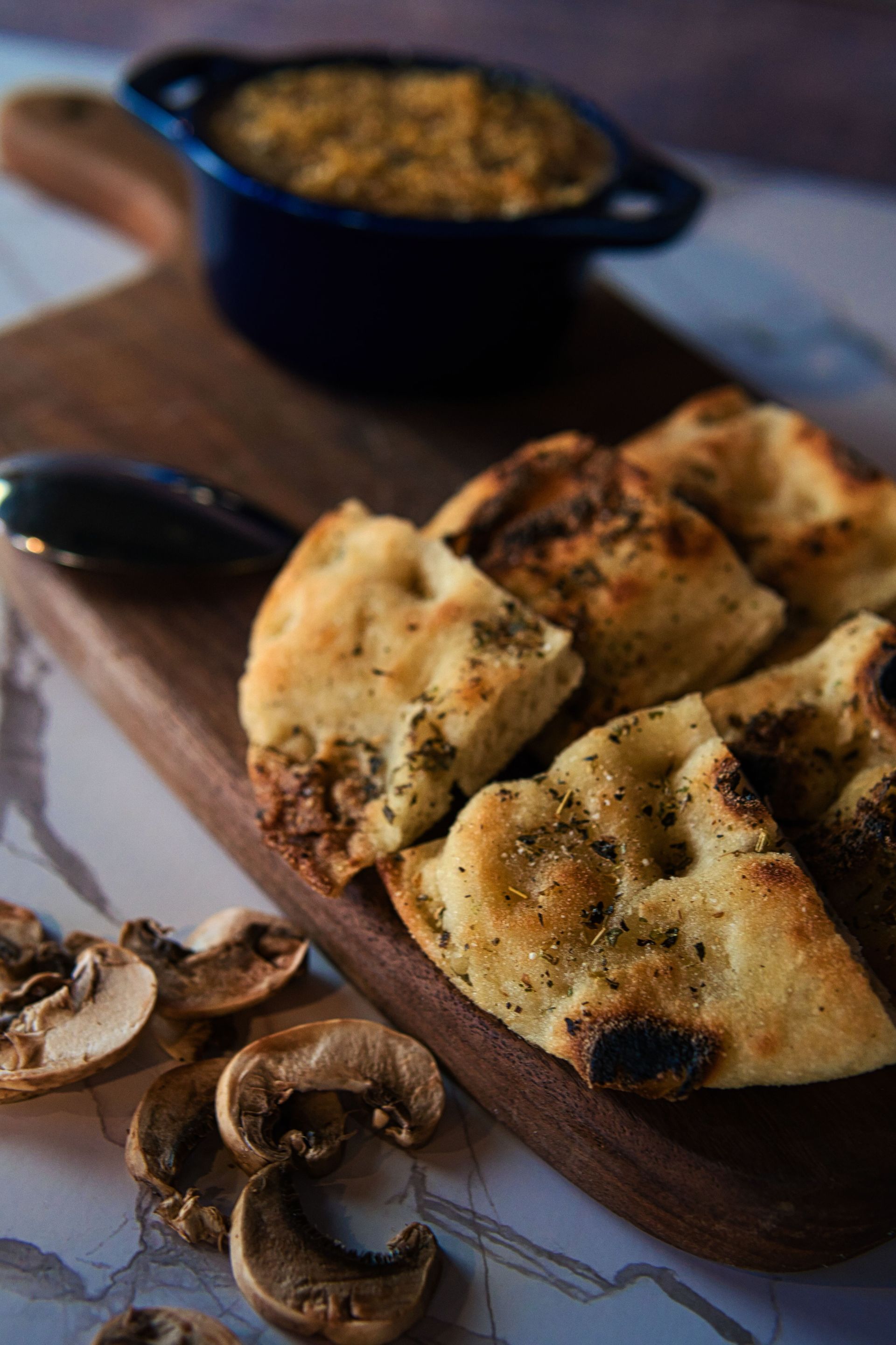 A wooden cutting board topped with bread and mushrooms.