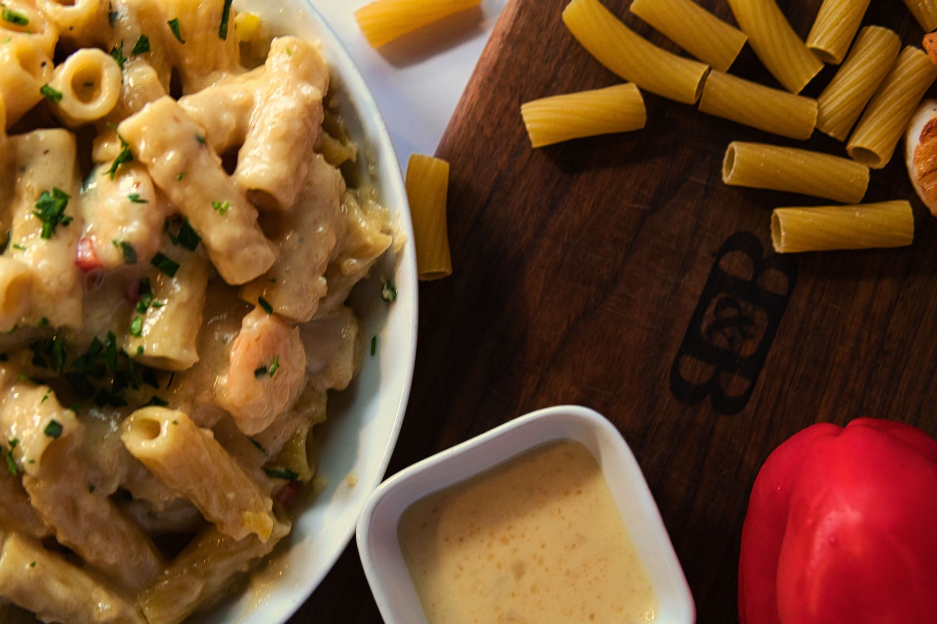 A bowl of pasta and a bowl of sauce on a wooden table.