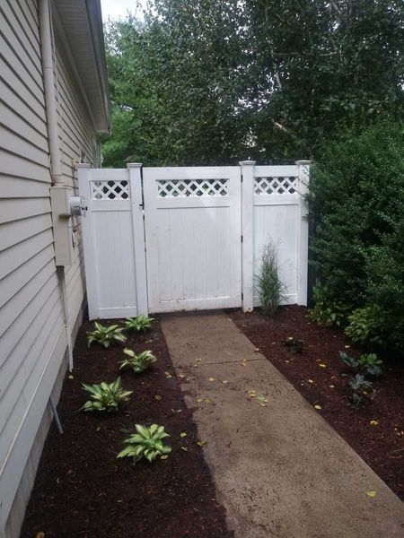 A white fence surrounds a walkway leading to a house