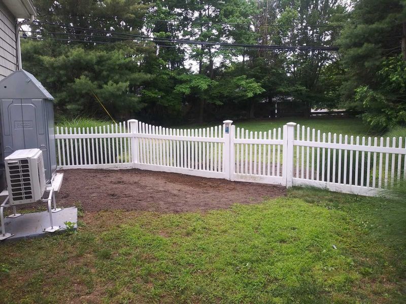 A white picket fence surrounds a lush green yard