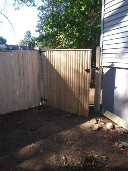 A wooden fence with a gate in the backyard of a house.