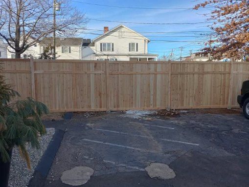 A person is using a high pressure washer to clean a wooden fence.