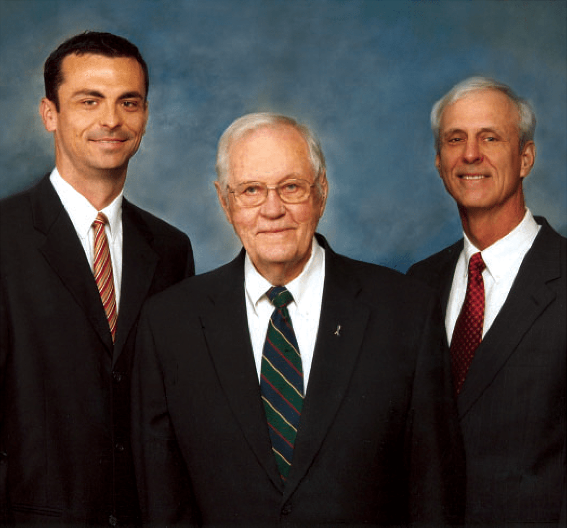 Three men in suits and ties pose for a picture