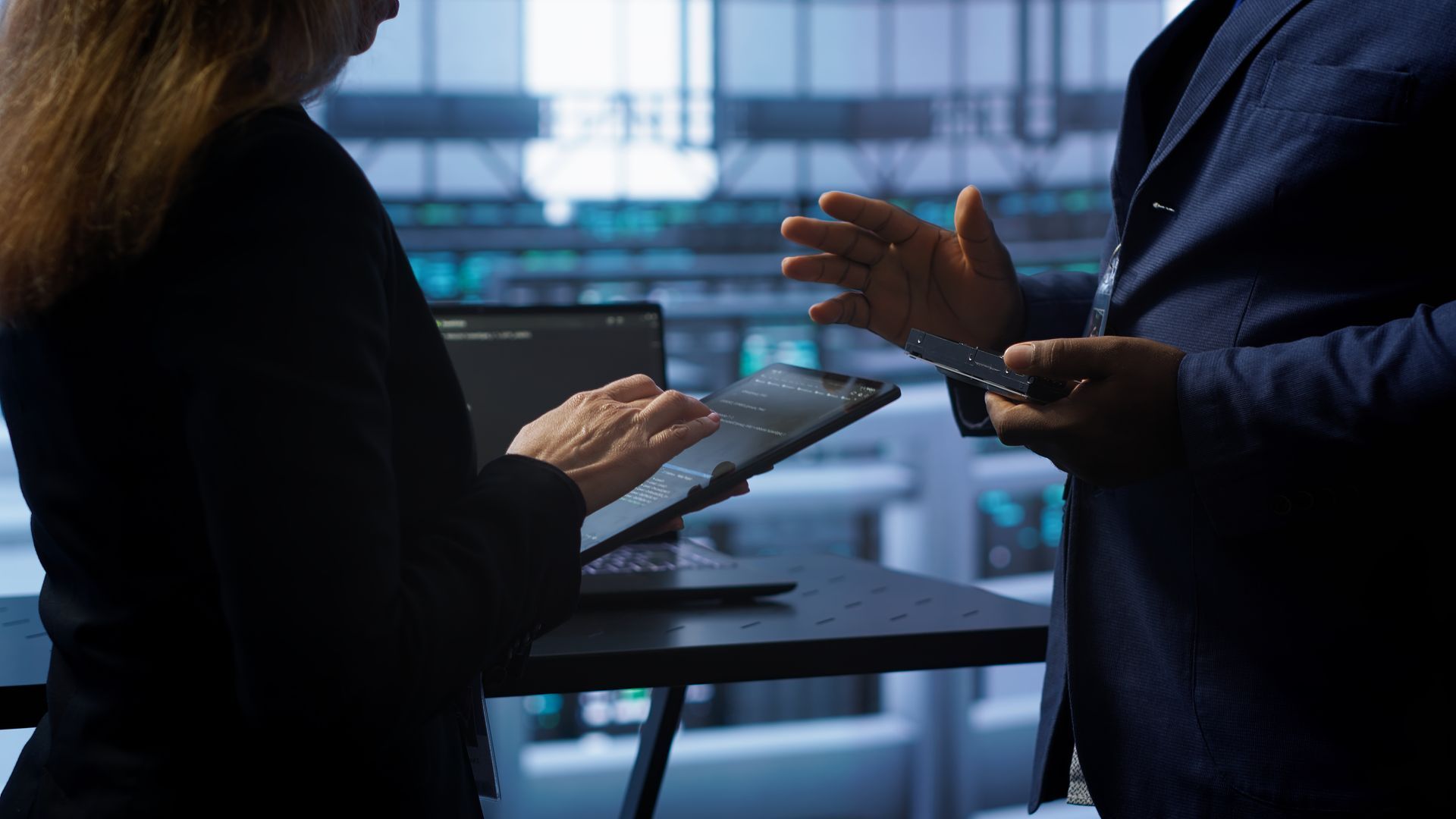 A man and a woman are standing next to each other looking at a tablet.