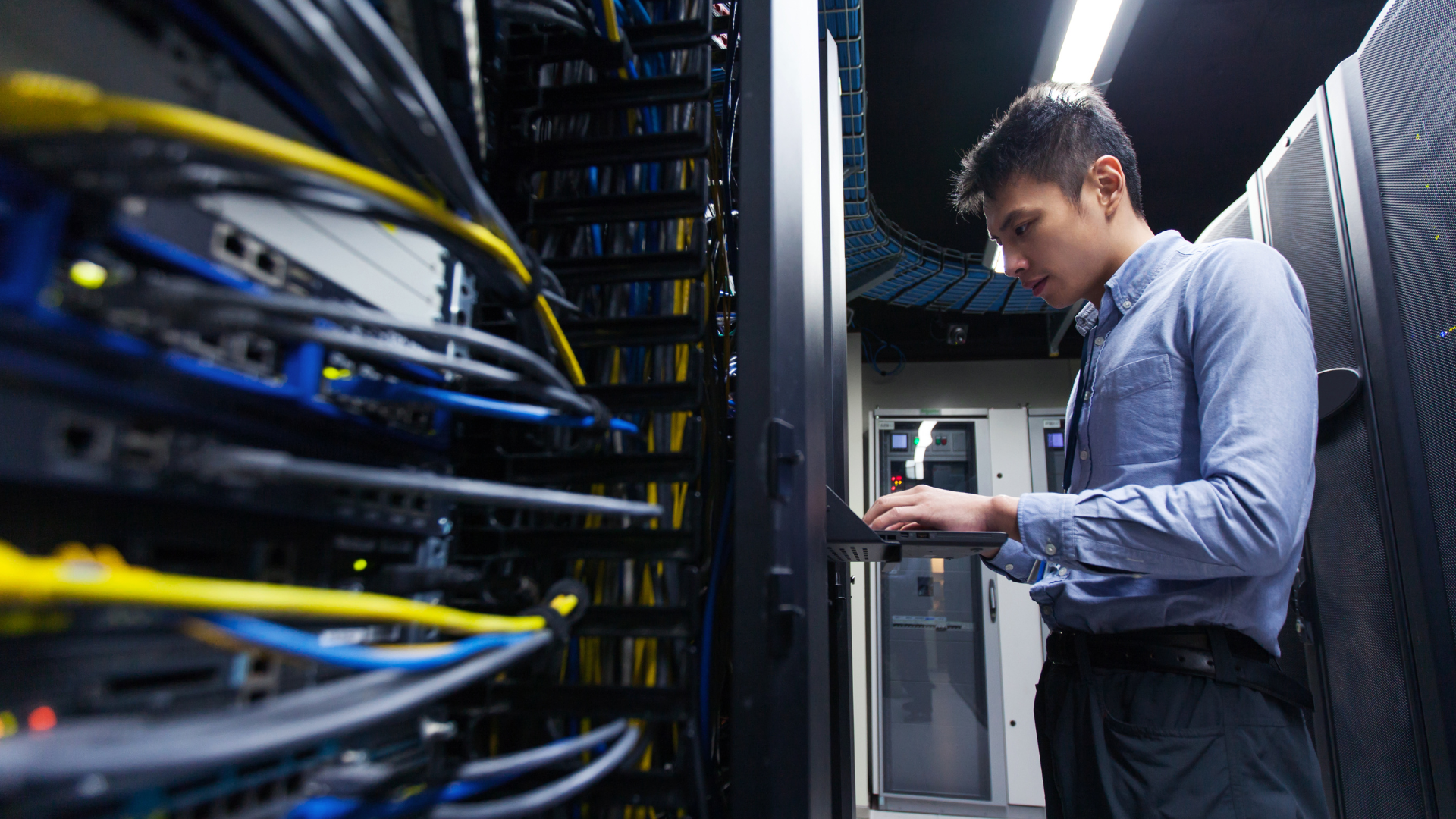 A man is working on a server in a data center.