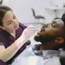 Smiling patient in a dental chair with a blue bib and green headrest