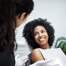Dentist speaking with smiling patient in a clinic, with gloves visible in the foreground