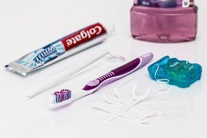 Toothbrush, toothpaste, dental floss, and mouthwash on a white surface
