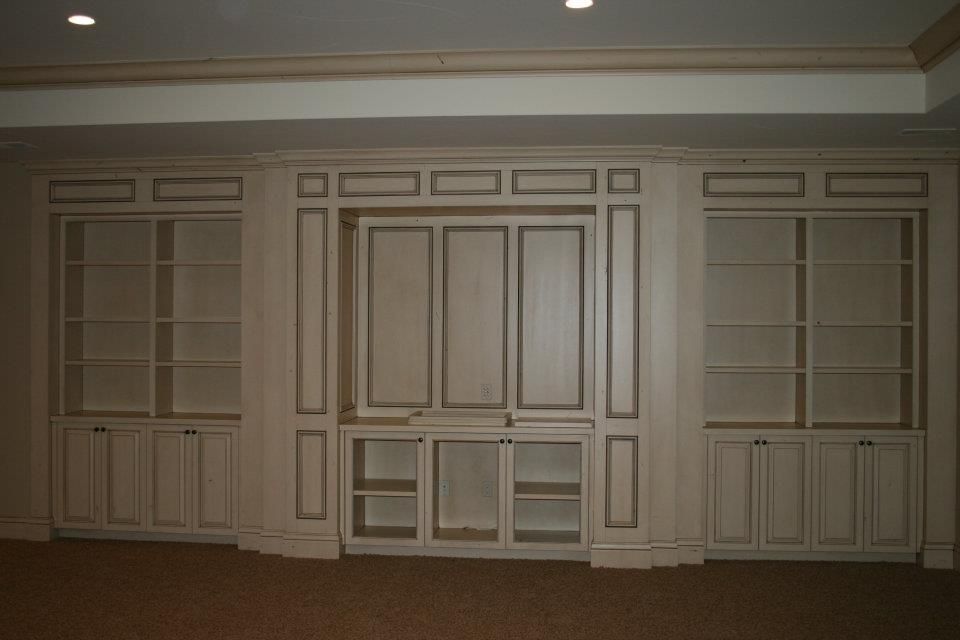 Built-in white shelving and cabinets against a wall, with a recessed center section, in a room.