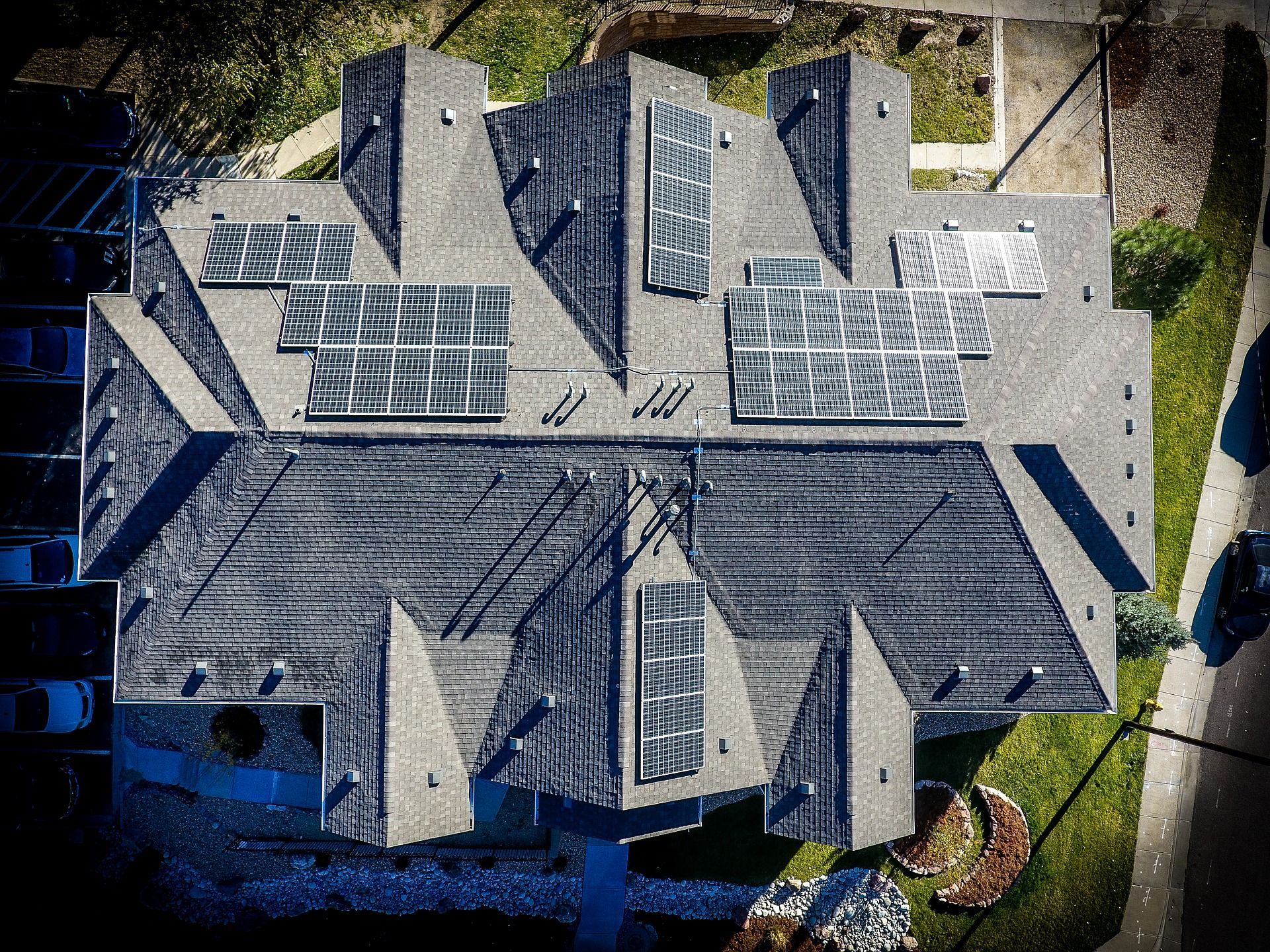Overhead view of a house with many angled roof sections; solar panels are installed on several sections.