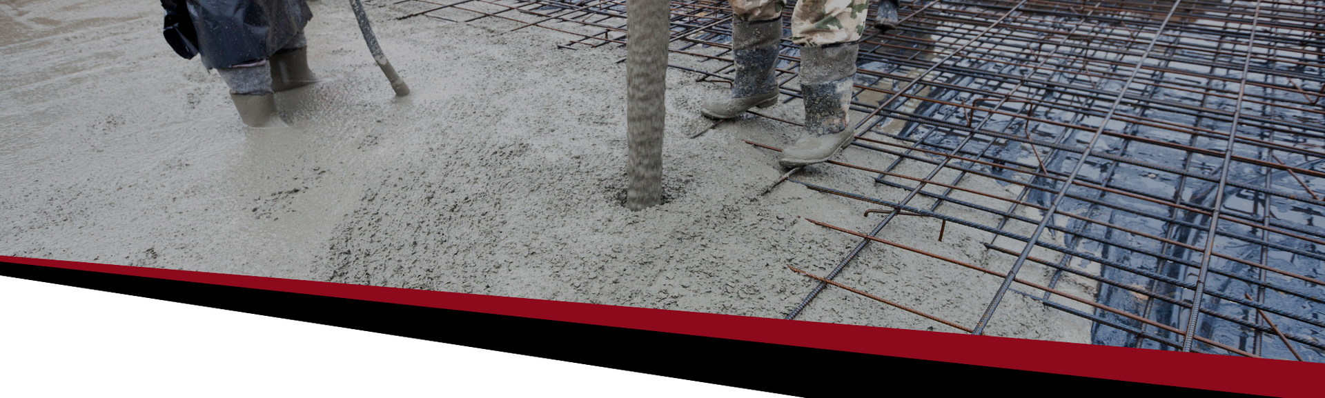 Construction site with workers, gravel ground, and a rebar grid along a red-edged barrier