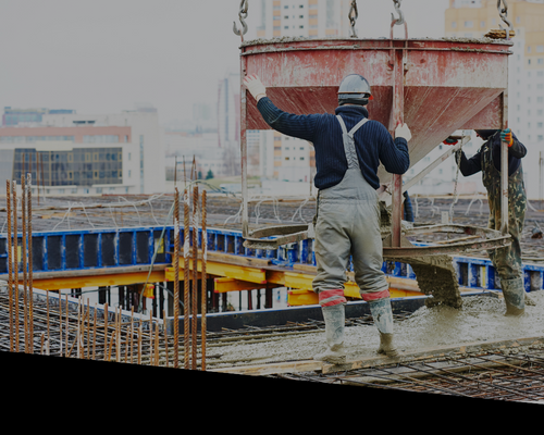 Construction worker directing a crane on a rooftop site with rebar and city buildings in the background