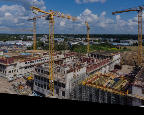 Construction site with cranes and an unfinished building under a blue sky