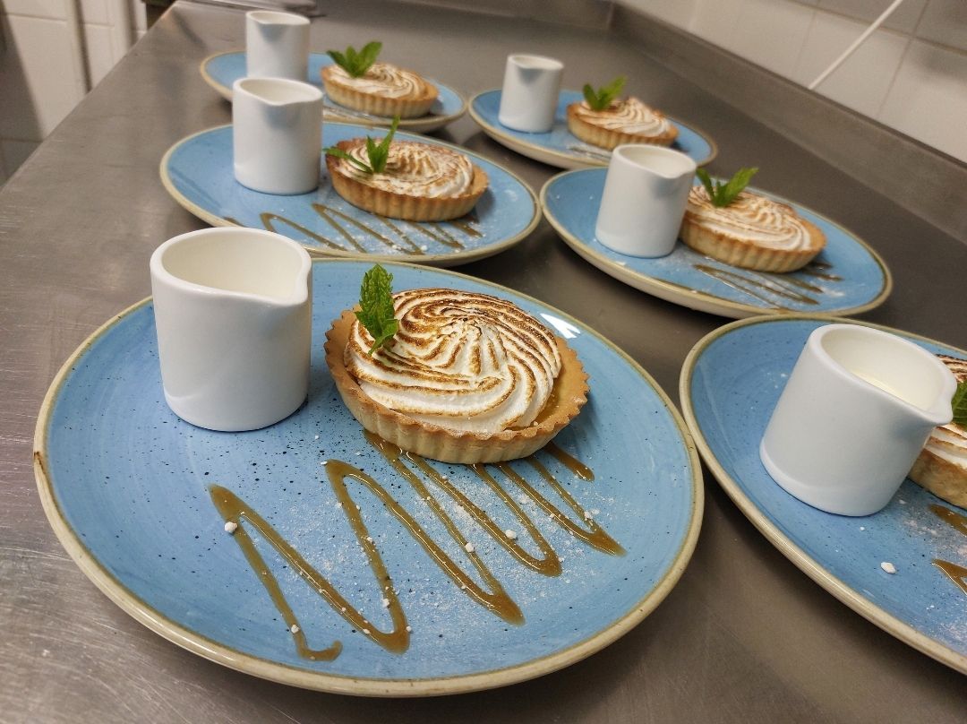 Individually plated desserts arranged neatly on blue plates, illustrating careful portioning and thoughtful presentation to reduce food waste in contract catering.