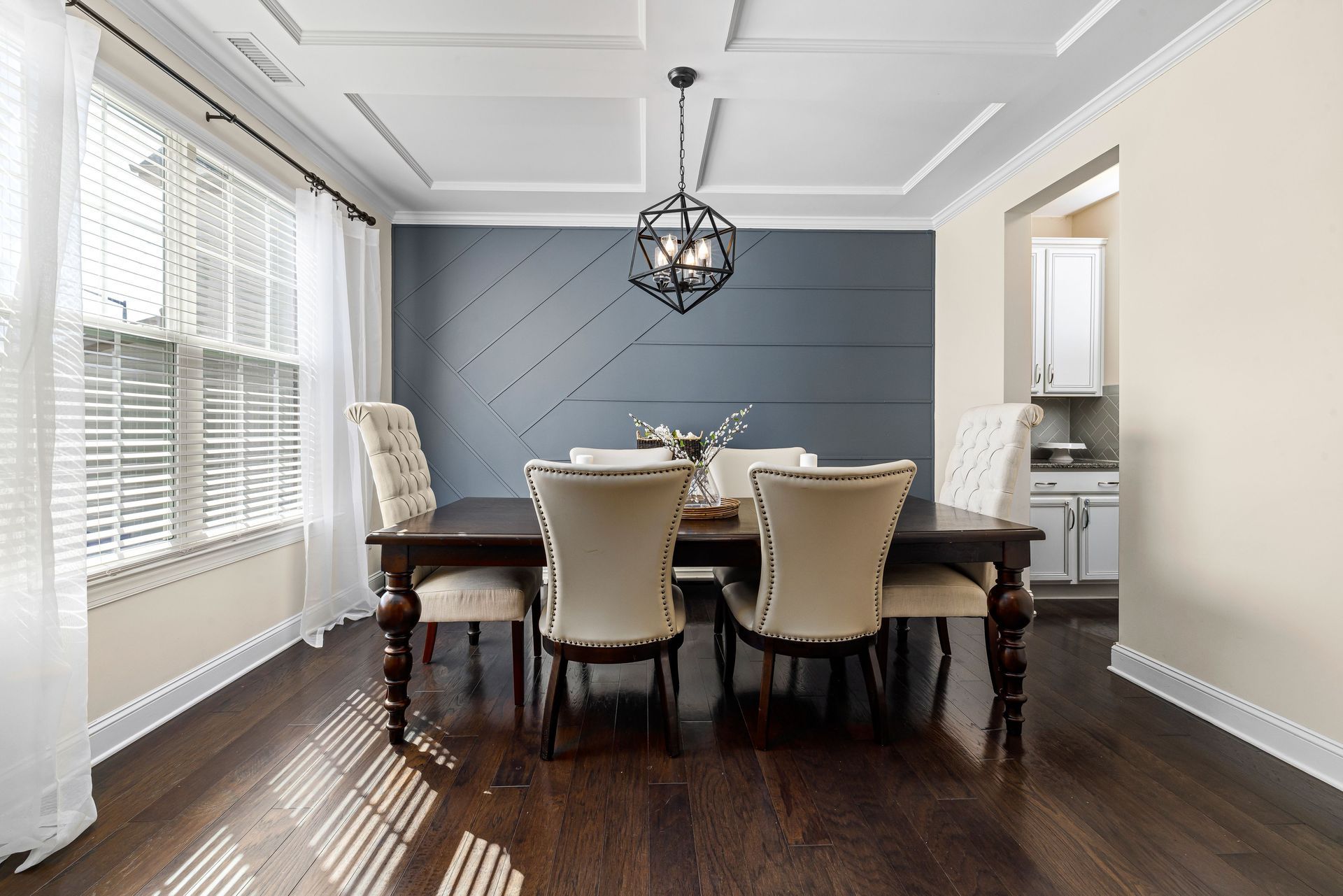 Elegant dining room with dark wood table, upholstered chairs, and large windows with blinds
