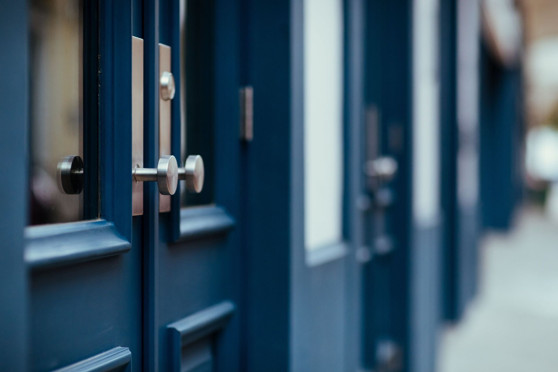 Row of blue doors with silver handles in a narrow hallway