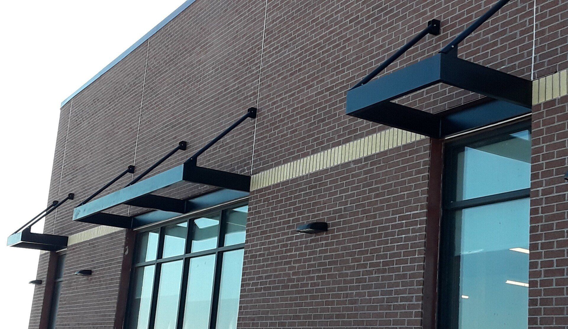 Brick storefront facade with black awnings above large windows and doors