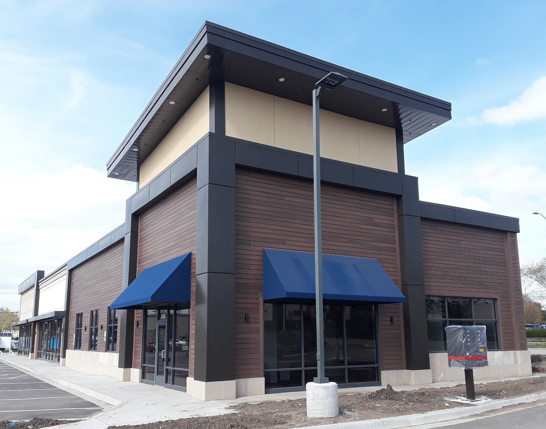 Modern brick commercial building with blue awnings and large windows under a clear sky