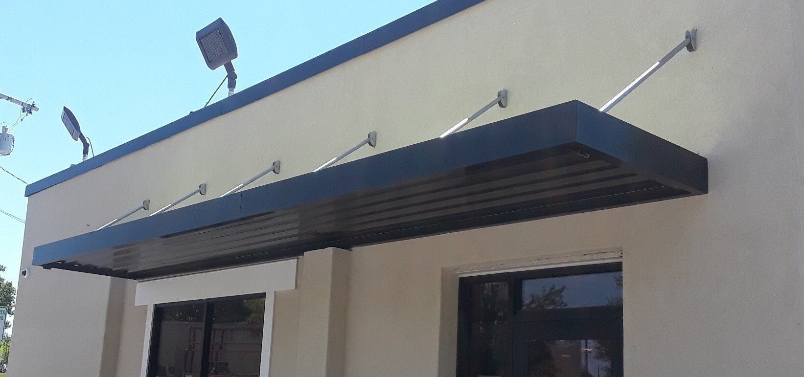 Blue awning over a beige building entrance against a clear sky