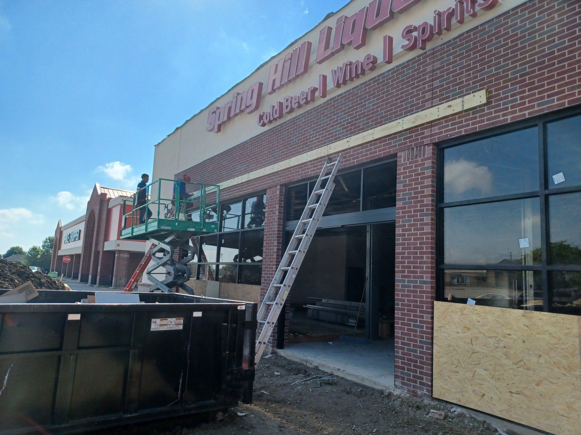Storefront under construction with ladder, scaffold, and boarded windows in a brick building