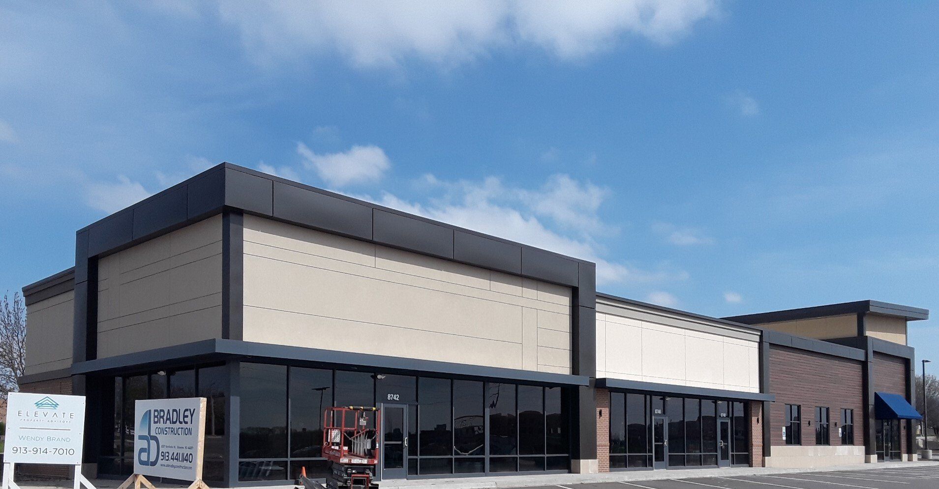 Modern commercial building exterior with dark trim and large glass windows on a sunny day