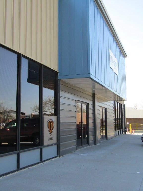 Modern commercial building exterior with beige and blue siding, glass windows, and a snowy sidewalk