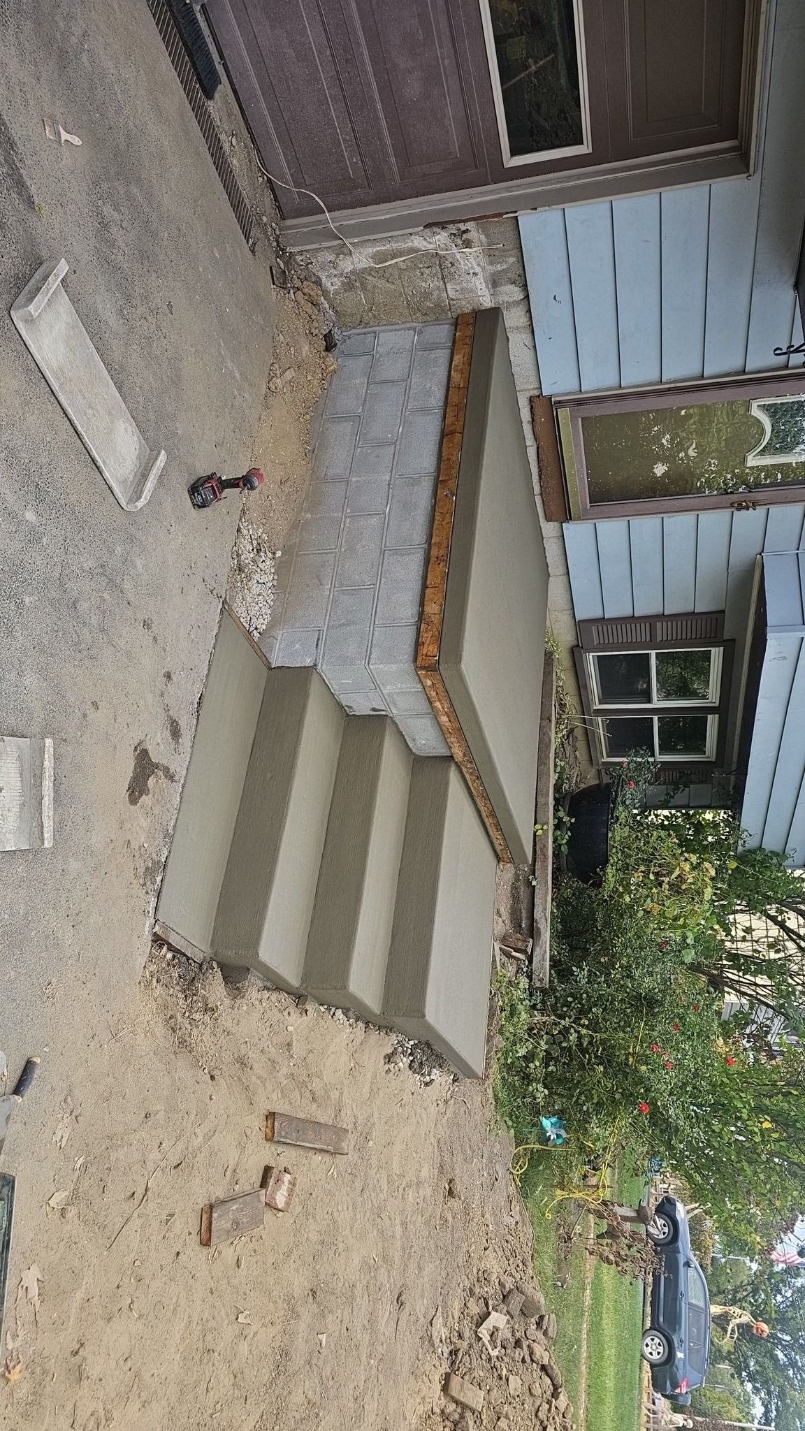 Concrete steps leading up to a house entrance. The steps are unfinished, and gravel surrounds.