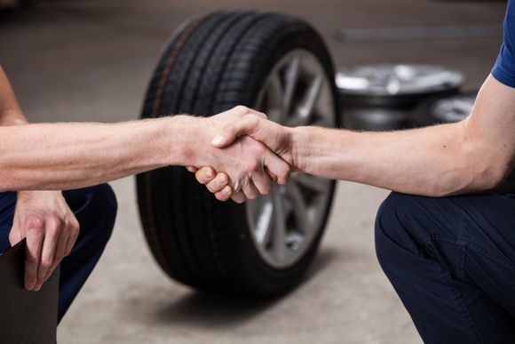 due persone che si stringono la mano e dietro una ruota