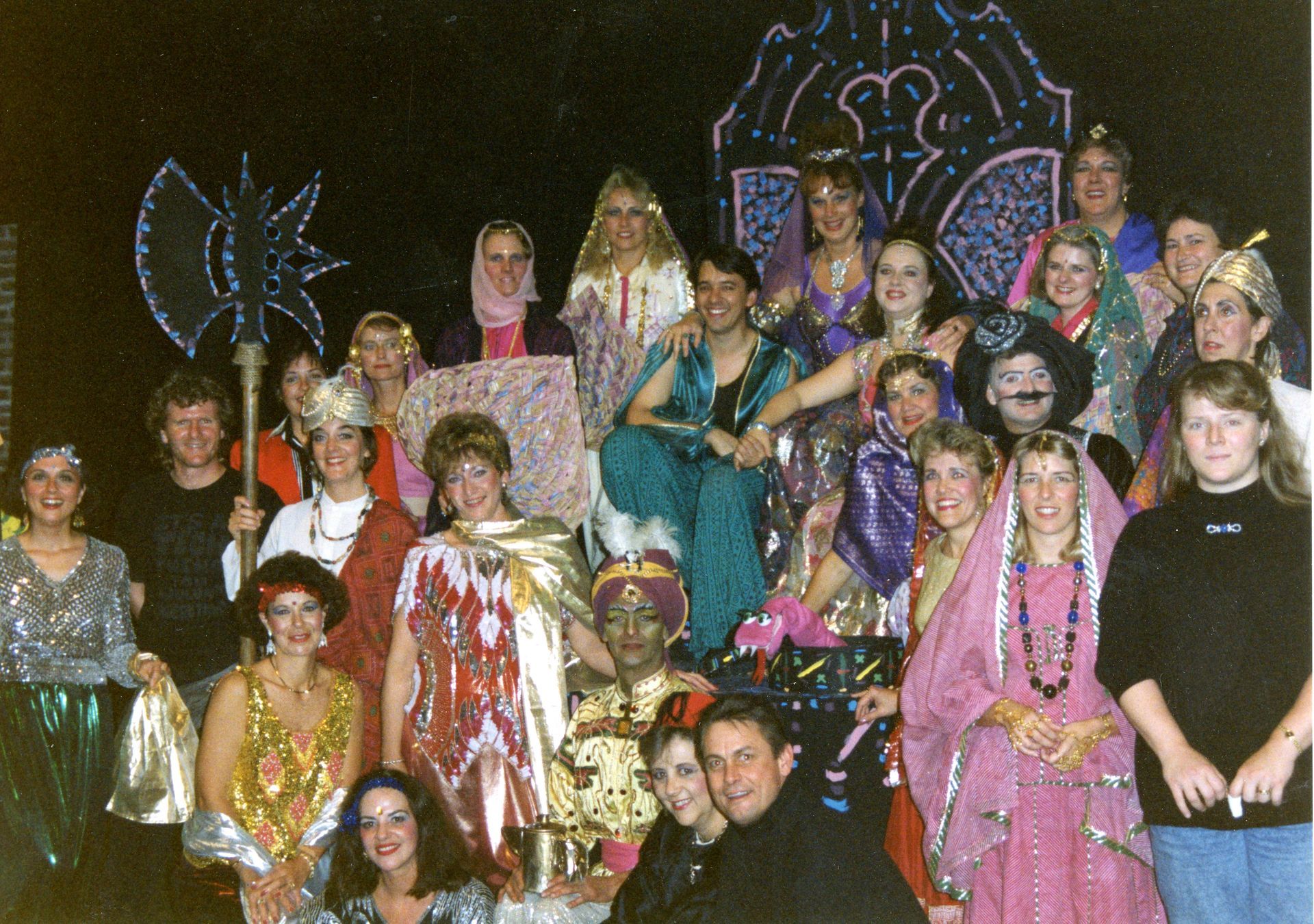 Group of people in colorful costumes posing on a decorated stage at a theatrical event