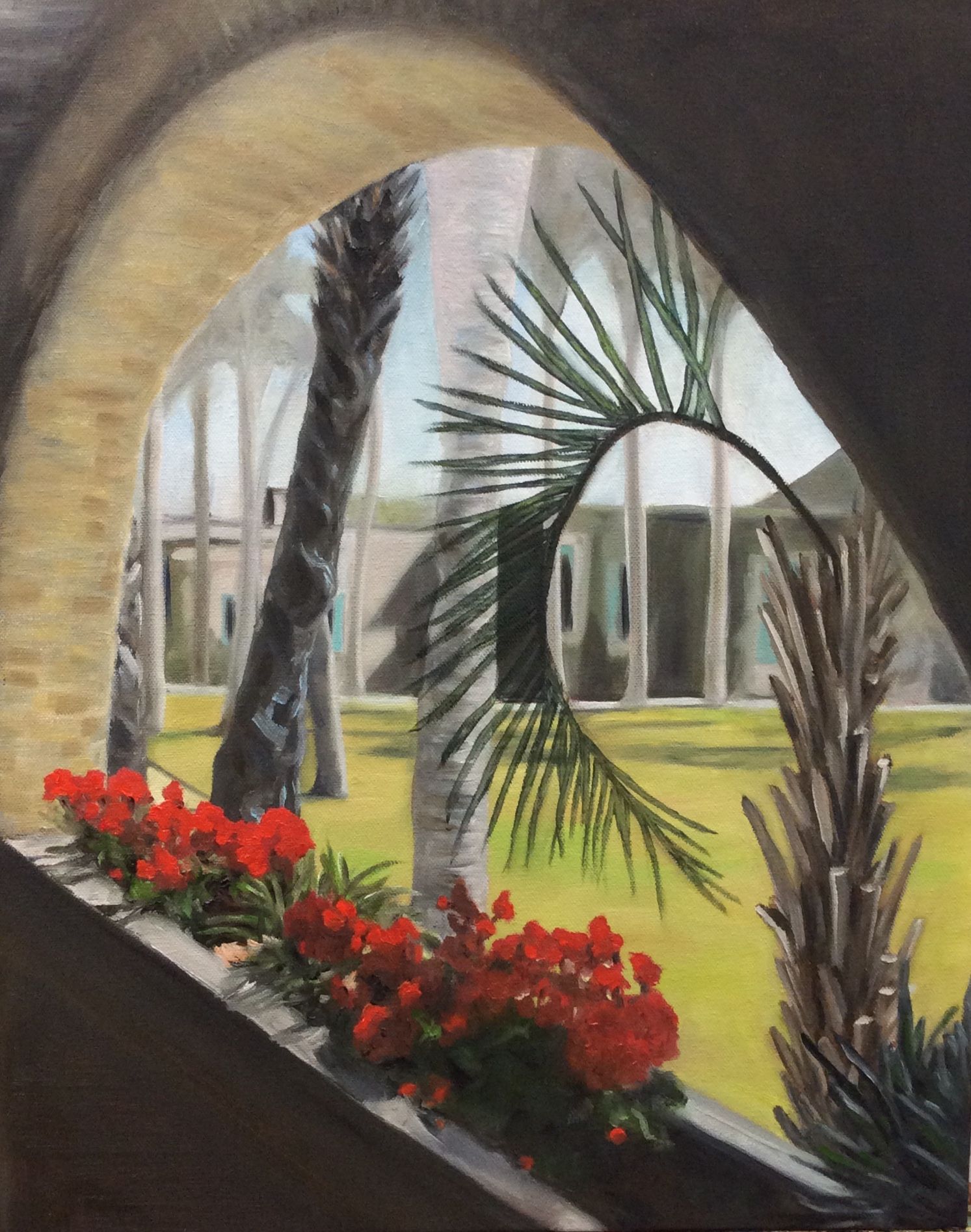 Courtyard view through an arch with palm trees, red flowers, and a modern building in the background