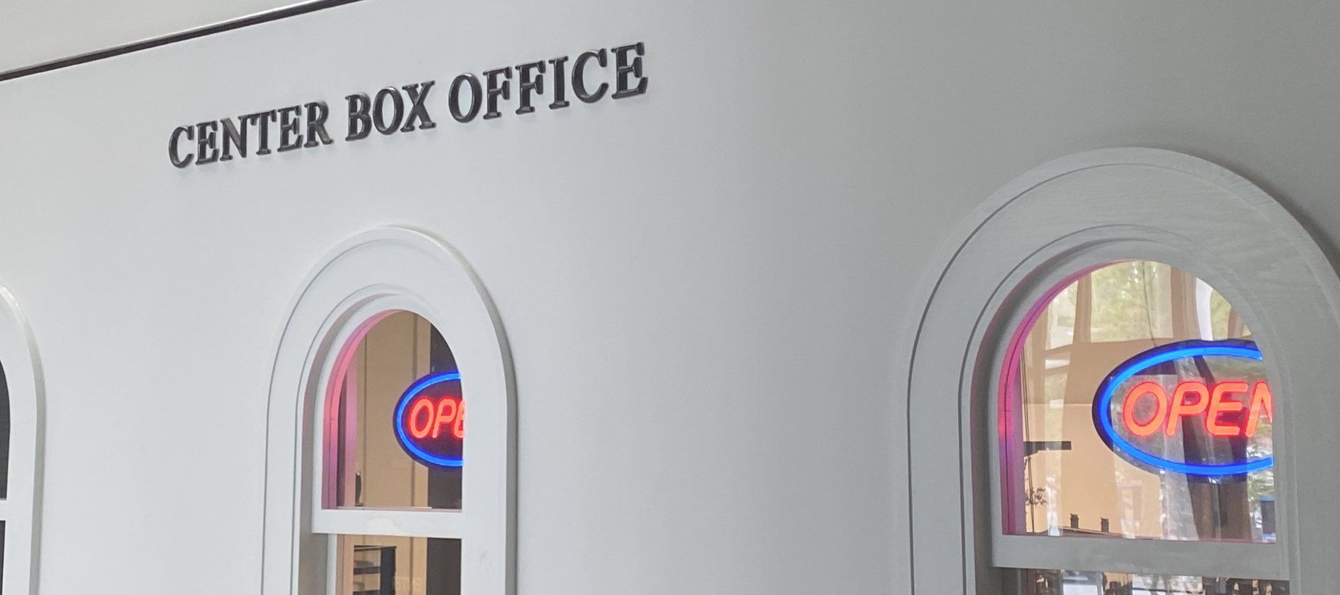 Center Box Office sign above arched windows with glowing open neon signs