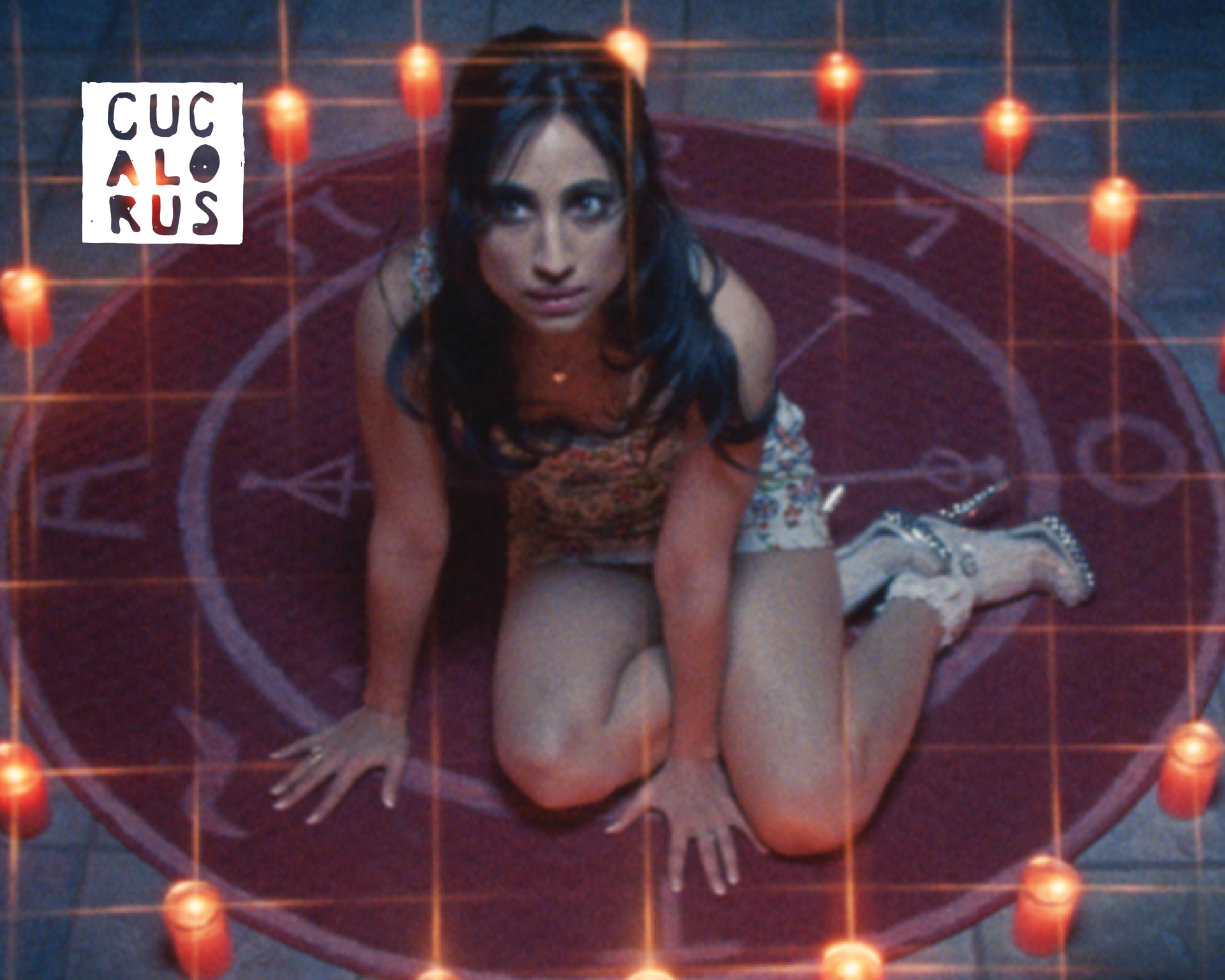 Woman kneeling on a glowing red circular pattern, lit by string lights in a dark, purple room.