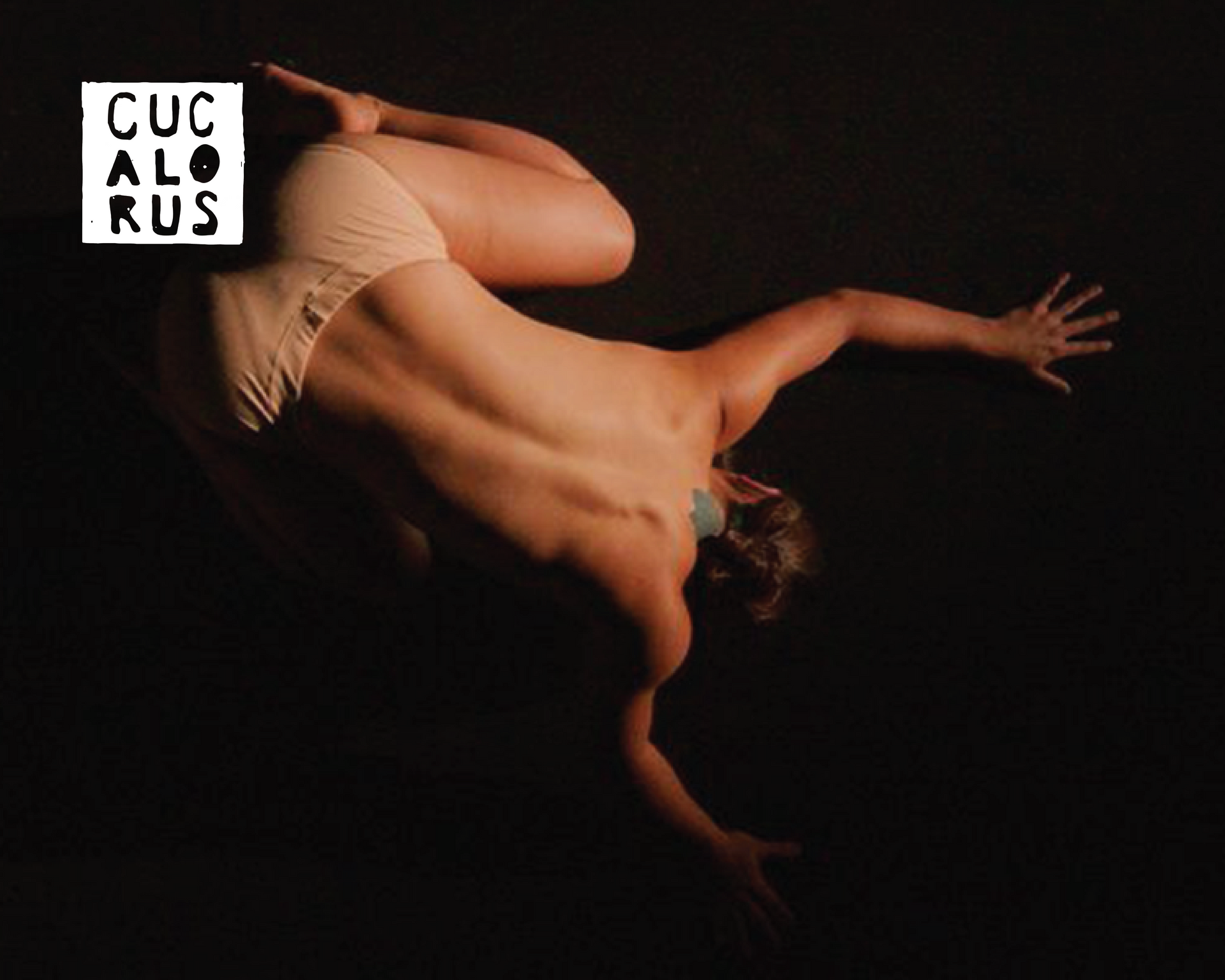 A nude dancer posed upside down in a dark studio, with a small white “CUC AL RUS” logo in the corner
