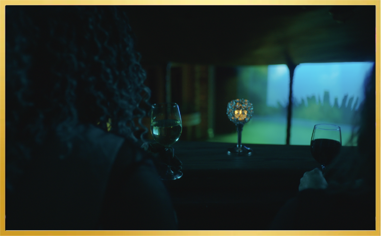 Two people seated at a dimly lit table, facing a neon-purple window with city silhouettes beyond.