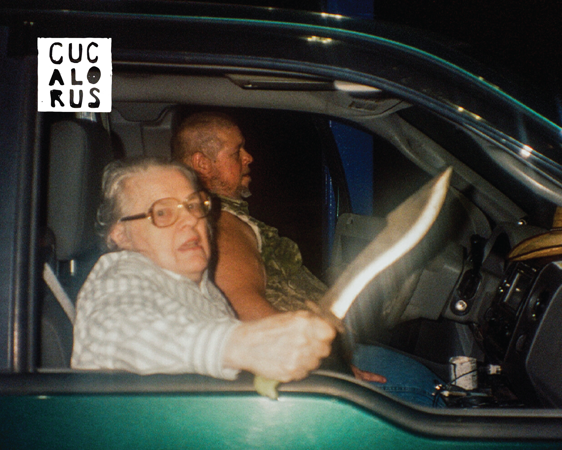 Two people inside a car at night; front passenger holds up a curved knife near the window.