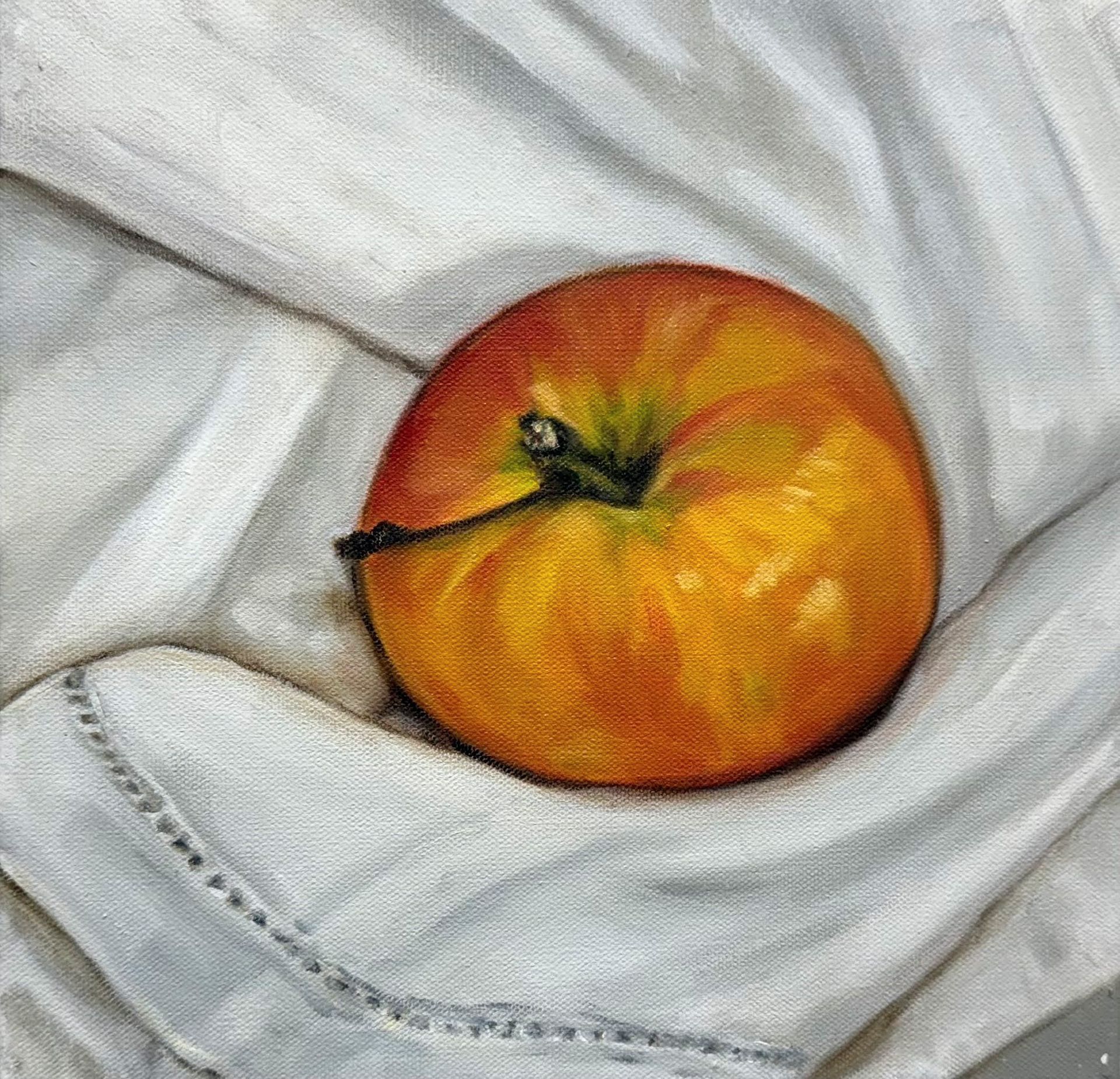An orange peach resting on wrinkled white fabric.