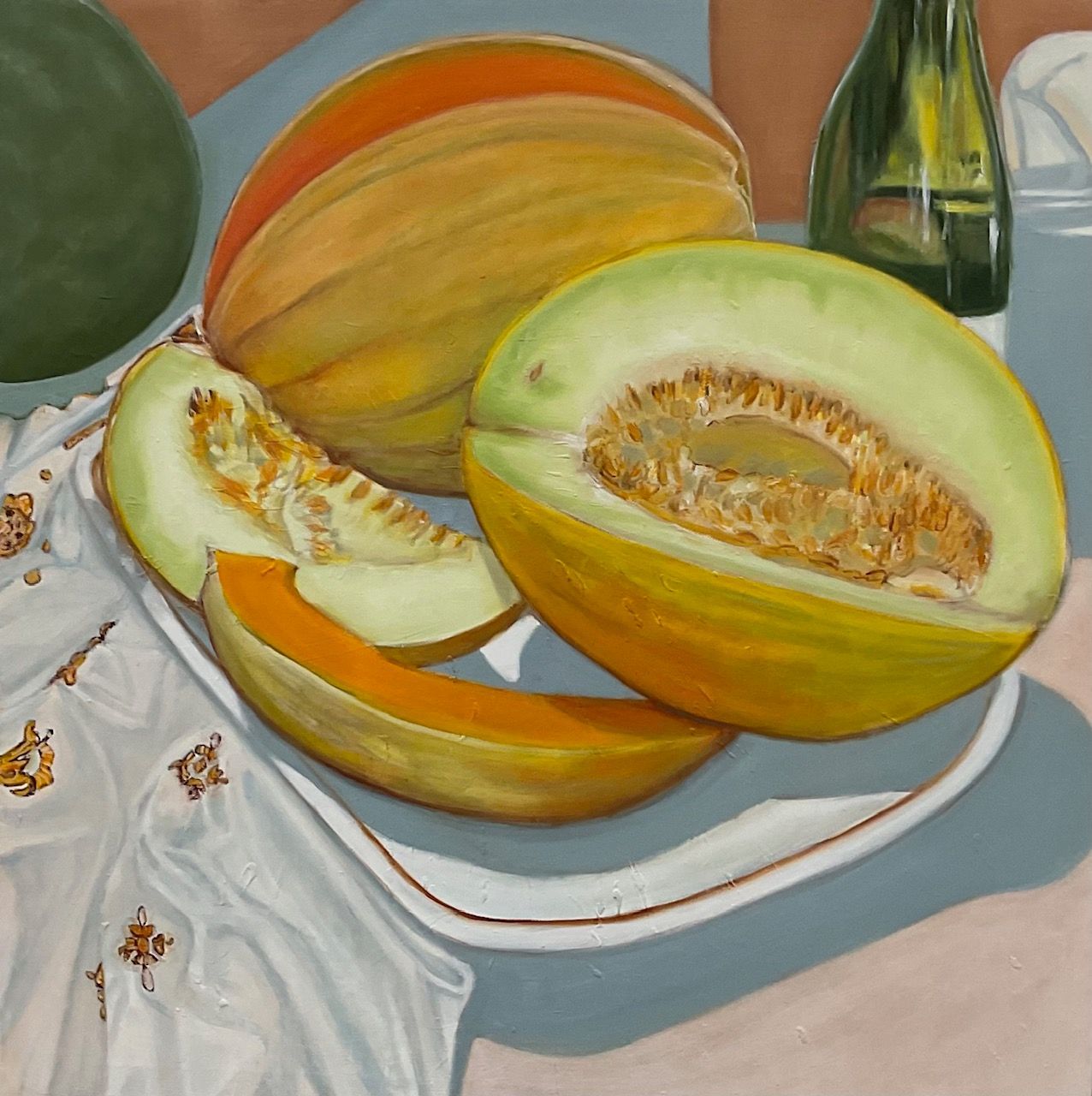 Melons and cantaloupe slices on a white plate with a draped cloth beside them
