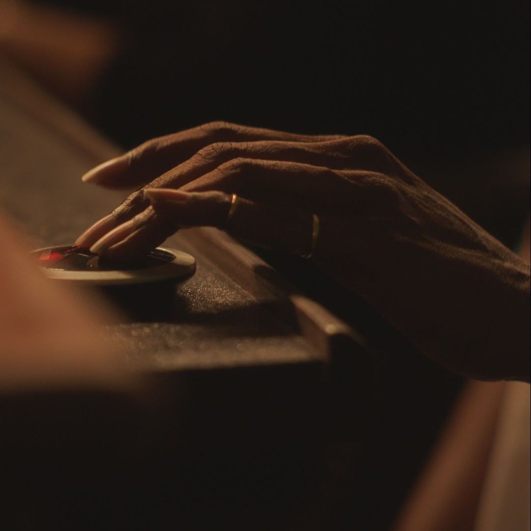 Hand resting on a dark control knob in warm, low light