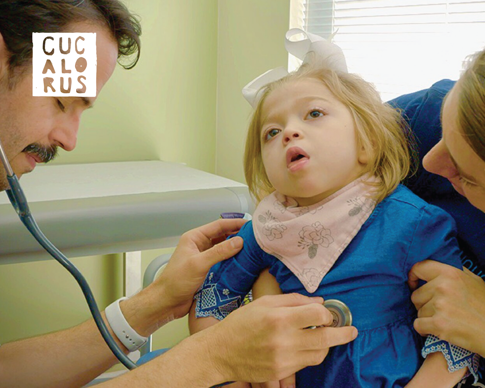 Doctor examining a child in a clinic while a caregiver holds them steady