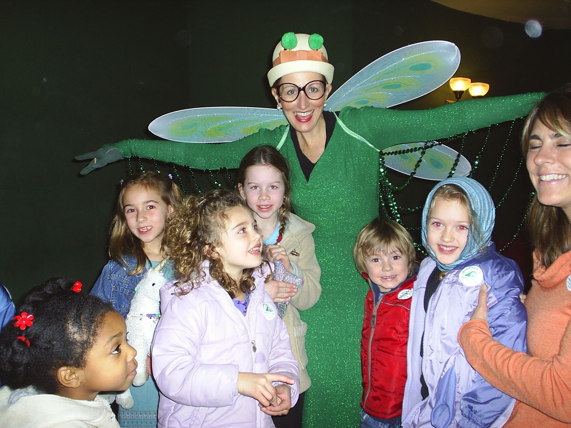 Costumed performer with wings smiling with children at a nighttime event