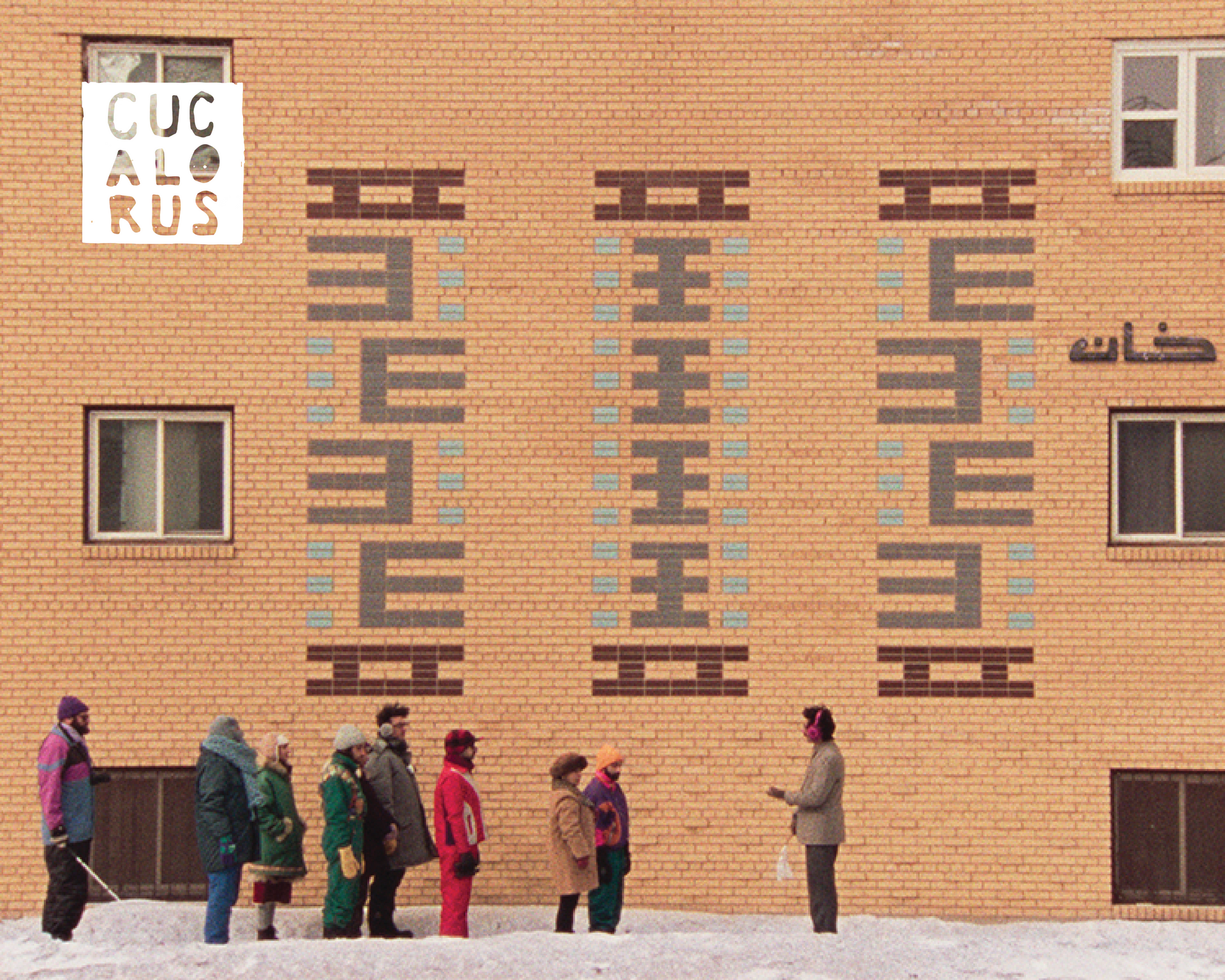 People walking past a brick building with large geometric murals in winter snow.